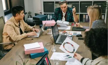 Team working on laptops and charts in a modern office – digital marketing company brainstorming session